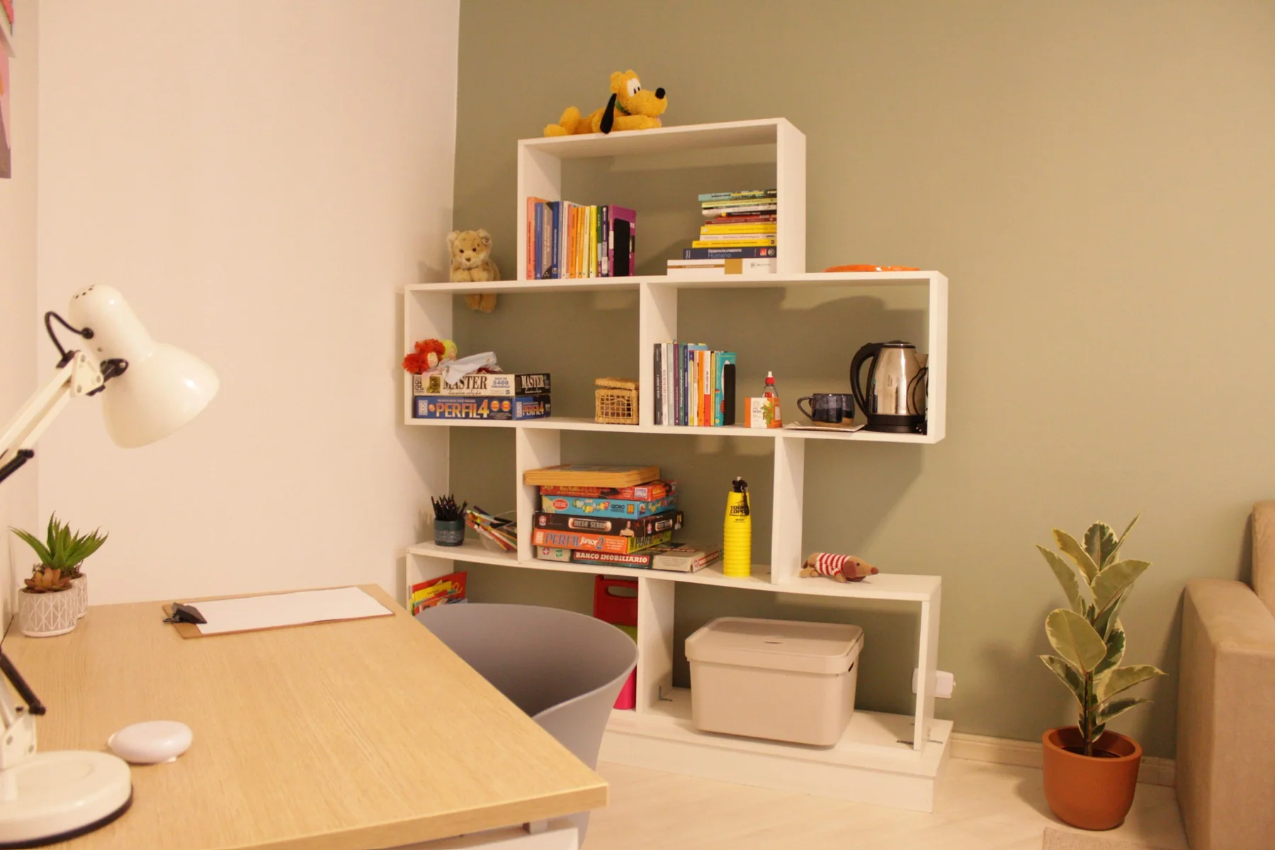 Consultório com mesa, estante, livros e materiais terapêuticos